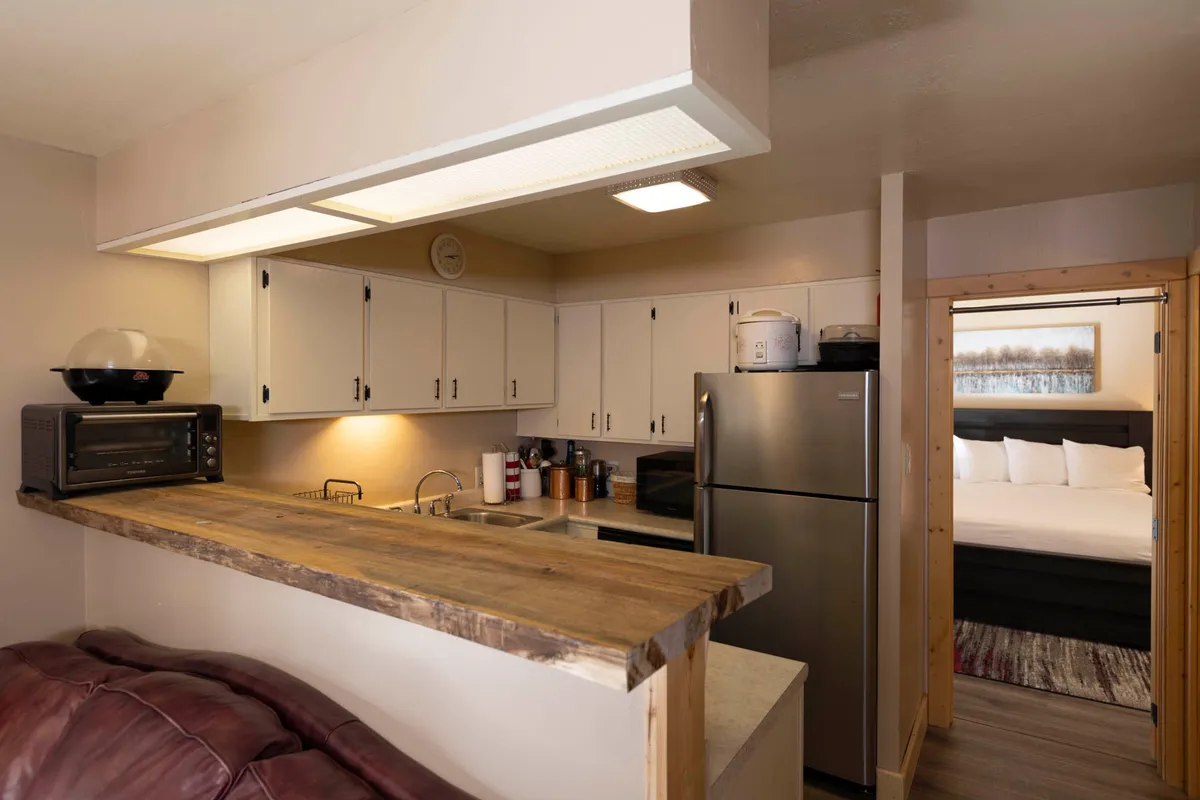 This image captures a home-style kitchen with a wooden countertop and modern appliances, all set within an open layout. The scene suggests a comfortable, inviting space ideal for preparing and sharing meals. You can almost imagine breakfast being served or a family gathering around for a late-night snack.